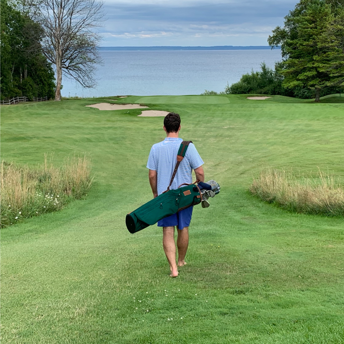 Green Sunday golf bag on barefoot walking golfer